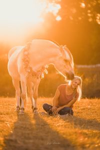 Pferd gibt lachender Frau einen Kuss