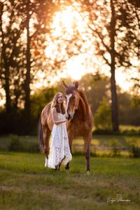 Pferd und Frau genießen den Sonnenuntergang