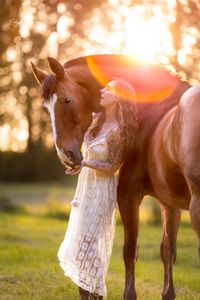 Frau posiert mit Pferd lachend in der Abendsonne